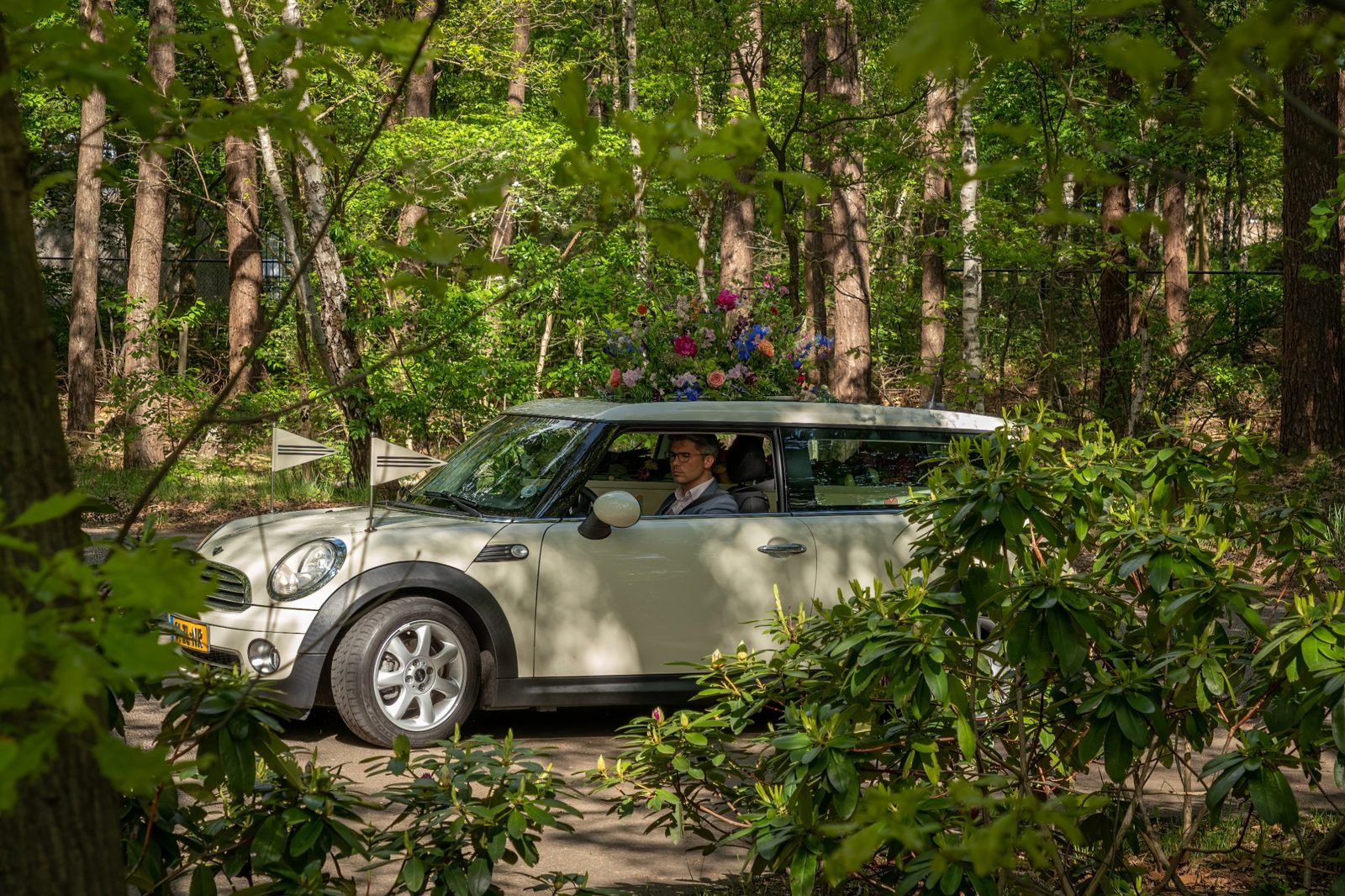 De Minirouwauto rijdt door het bos, met bloemen op het dak